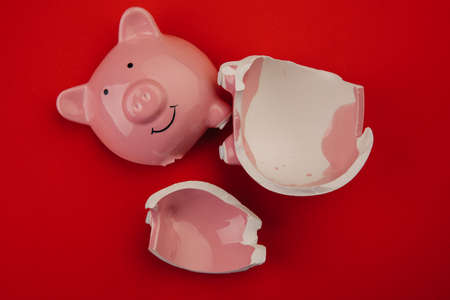 Broken piggy bank on red backgroundの写真素材