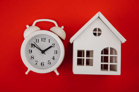 Alarm clock with house model on red backgroundの写真素材