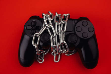 Game addiction concept. Gamepad is tied by chain