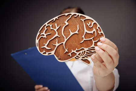 Doctor holding wooden brain close-up. The importance of early diagnosis conceptの写真素材
