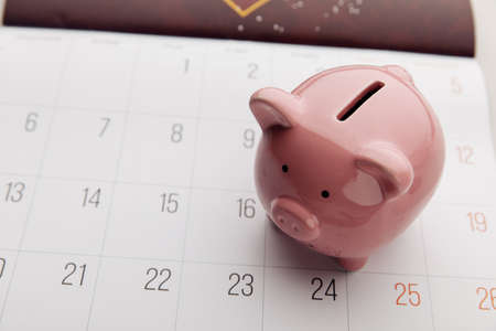 A piggy bank on a white calendar background, time to start savingの写真素材