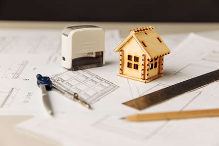 Blueprint with wooden house, drawing tools and glasses on a tableの写真素材