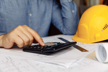 Building concept. Civil male engineer using calculator for analysis in the officeの写真素材