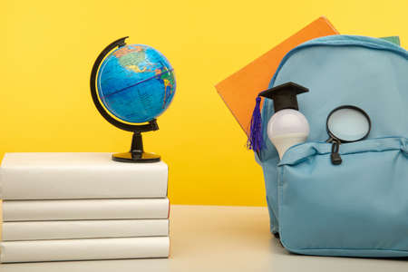 Blue school backpack, globe and bulb on a tableの写真素材