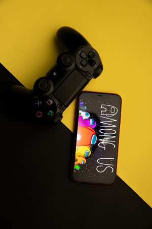 Tula, Russia - April 08, 2021: Among Us logo on iPhone display and PS gamepadのeditorial素材