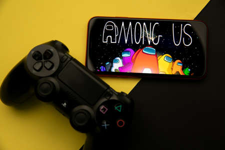 Tula, Russia - April 08, 2021: Among Us logo on iPhone display and PS gamepadのeditorial素材