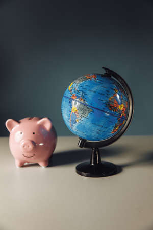 Piggy bank and globe on a table. International business concept. Vertical image