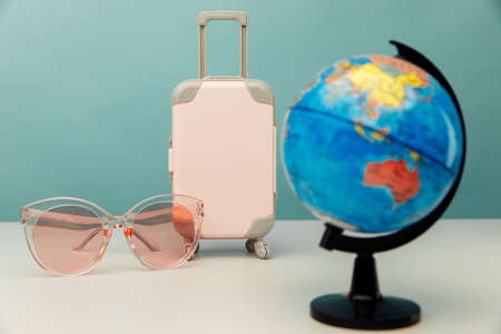Plastic travel suitcase, pink glasses and globe close-up. Travel conceptの写真素材
