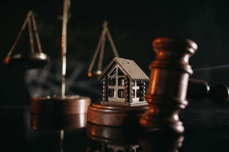 Auction or law concept. Wooden house and judge gavel on a glossy table close-upの写真素材