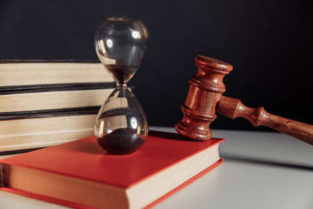 Judge gavel and hourglass on red book close-up. Law conceptの写真素材