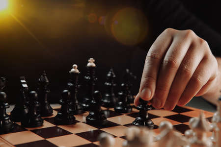 Close-up chess board with hand holding black pawn