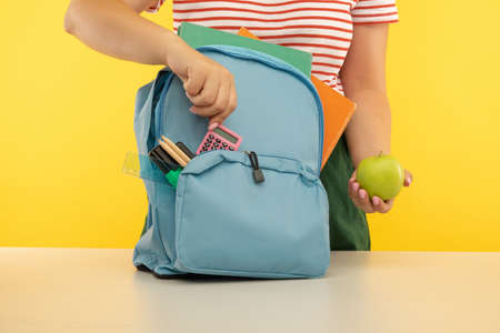 Young girl packing blue backpack. Back to school conceptの写真素材