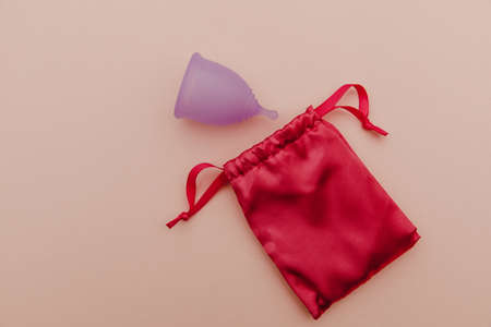 Reusable pastel purple menstrual cup and bag on a pink background. Ecology and recycling conceptの写真素材