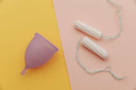 Menstrual cup and tampons on a yellow pink background. Concept of womens healthcare and hygieneの写真素材