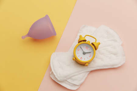 Menstrual cup and pads with alarm clock. Womens hygiene conceptの写真素材