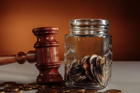 Coins from a jar and legal gavel on a table close-upの写真素材
