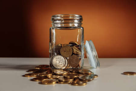 Glass jar with coins on a table. Savings conceptの写真素材