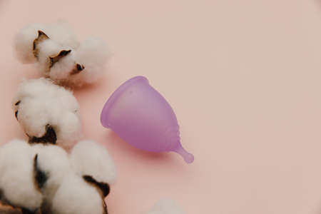 Reusable pastel purple menstrual cup on a pink background. Alternative way of womens hygiene, menstruation, critical daysの写真素材