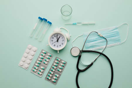 Alarm clock and medical tools on blue background, top view. Healthcare and early diagnostic conceptの写真素材