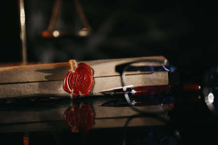 Document with wax seal, scales and antique stamp on a desk. Last will and legacy concept