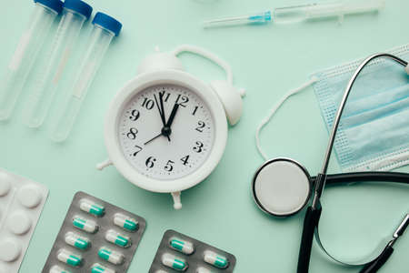 Alarm clock and medical tools on blue background close-up, healthcare and early diagnostic conceptの写真素材