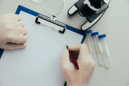 A scientist sitting at a table in a laboratory with test-tubesの写真素材