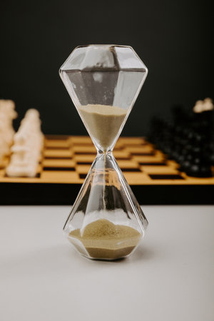 Hourglass and chess pieces on a grey background. Sports and leisure concept. Vertical imageの写真素材