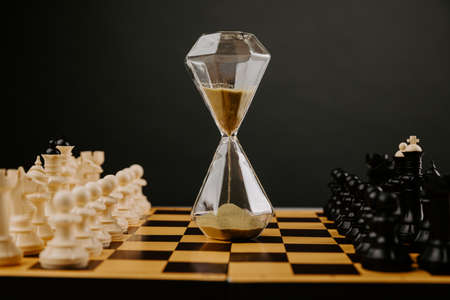 Hourglass in chess game, competition success play. Strategy, management or leadership concept