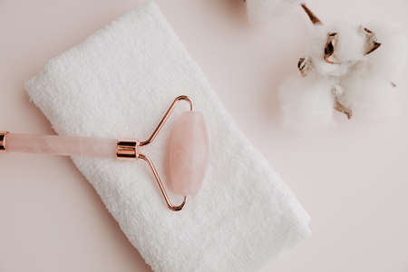 Jade face roller with towel on a pink background, face therapy conceptの写真素材