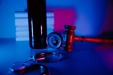 Alcohol addiction and crimes concept. Bottle of whiskey and jar of beer with gavel and handcuffsの写真素材