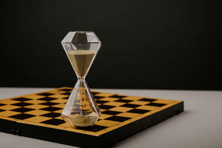 Hourglass on a chessboard. Time and strategy themeの写真素材
