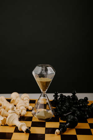 Hourglass and chessboard with figures. Strategy, management or leadership concept. Vertical imageの写真素材