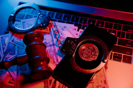 Golden bitcoin with handcuffs and gavel on laptops keyboard. Cryptocurrency conceptの写真素材