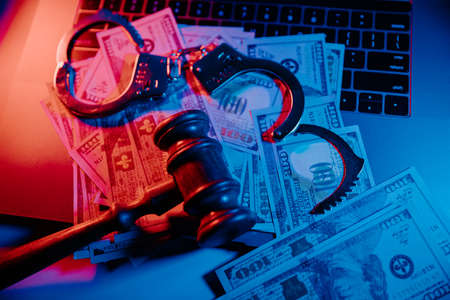 Cyber crime, online piracy and internet web hacking concept. Handcuffs with gavel on a keyboardの写真素材