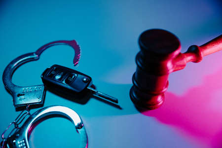 Car key, gavel and handcuffs in neon light. Dangerous driving and law conceptの写真素材