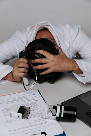 Burnout doctor lays in medical office with a stethoscope on the table. Vertical imageの写真素材