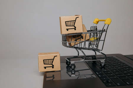 Online sales concept. Trolley with paper boxes on a keyboardの写真素材