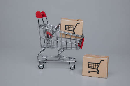 Shopping and delivery concept. Mini shopping cart with shipping paper boxes.の写真素材