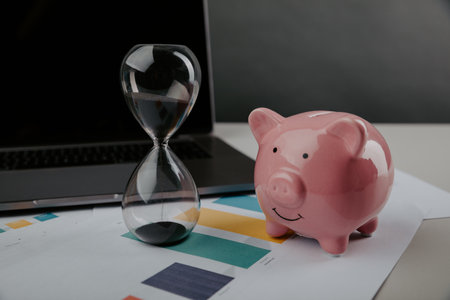 Piggy bank with hourglass and laptop close-up. Online business and dedline conceptの写真素材