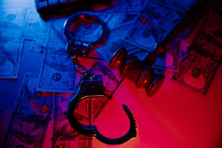 Law gavel with dollars and handcuffs on a table. Top view. Fraud or crime conceptの写真素材