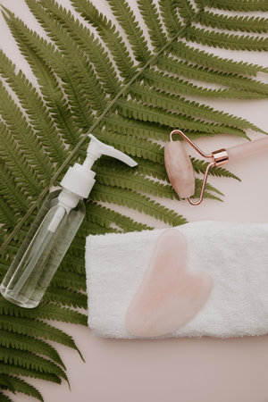 Jade face roller and guasha with towel on a fern leaf. skincare concept. vertical image.の写真素材
