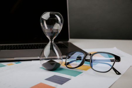 Hourglass on a workplace close-up. Time management concept.の写真素材