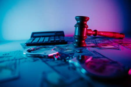 Judges gavel and handcuffs with dollar bill in neon llightの写真素材