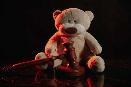 Wooden gavel and teddy bear in a dark court room. Law and children conceptの写真素材