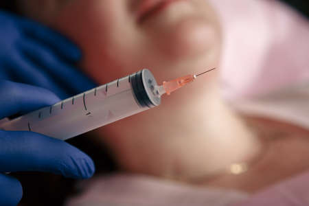 Cosmetologist injecting ozone to chin. Patient is sitting in chair with closed eyes. This therapy is purposed to increase oxygen in a body.の写真素材