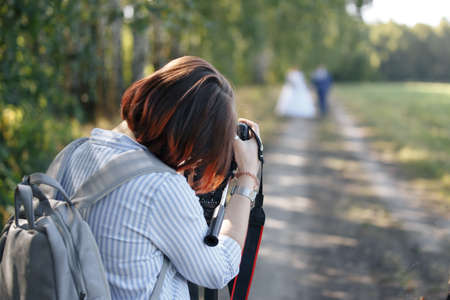 a wedding photographer takes pictures of the bride and groom in nature, the photographer in actionの写真素材