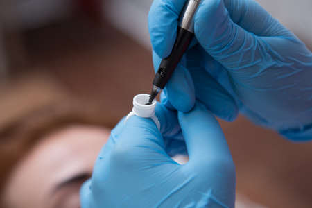manual master with a tool for tattooing eyebrows. Professional female eyebrow tattooの写真素材