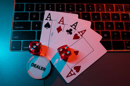 Online casino and gambling business concept. Cards and dice on laptops keyboard