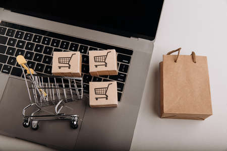Cardboard boxes with a cart on a keyboard and shopping bag. Shopping service on the online webの写真素材