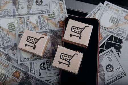 Card package boxes and smartphone on dollar banknotes. Online shopping and delivery conceptの写真素材